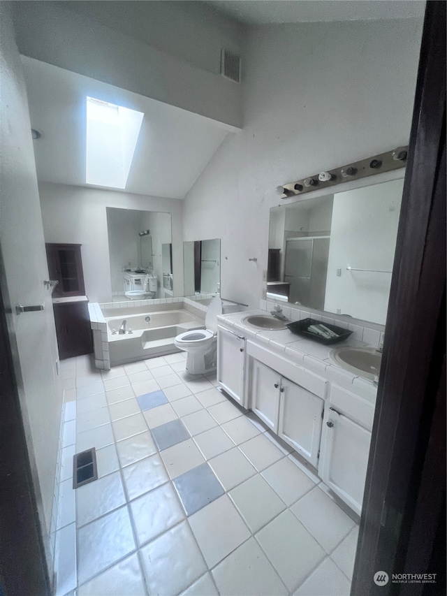 kitchen with vaulted ceiling with skylight, light tile flooring, white cabinetry, and sink