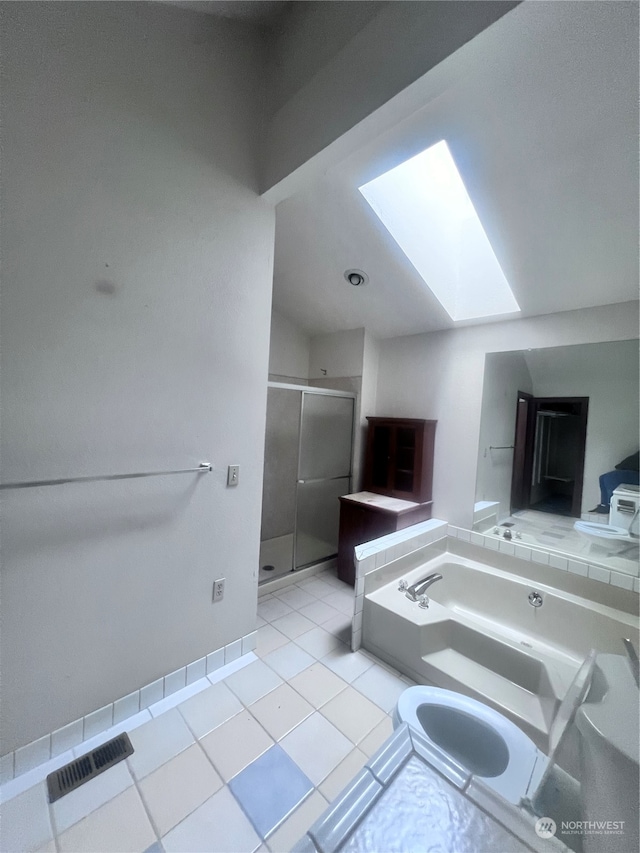 bathroom featuring a skylight, tile flooring, and separate shower and tub