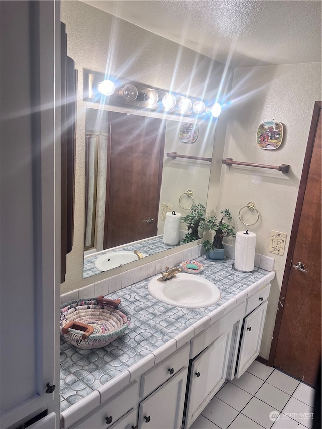 bathroom with a textured ceiling, tile floors, and vanity