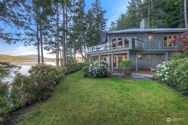 back of house featuring a yard and a deck with water view