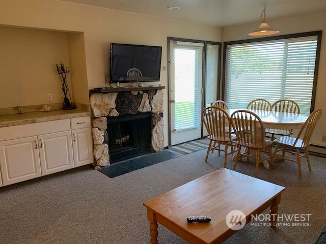 carpeted living room featuring a stone fireplace