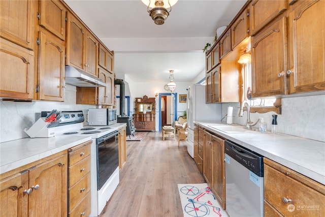 kitchen featuring pendant lighting, light hardwood / wood-style floors, stainless steel appliances, sink, and decorative backsplash