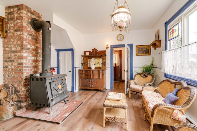 living room featuring a notable chandelier, light hardwood / wood-style flooring, and a wood stove