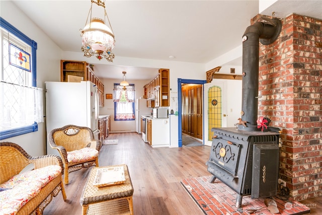 living area featuring a wood stove, light wood-type flooring, and a chandelier