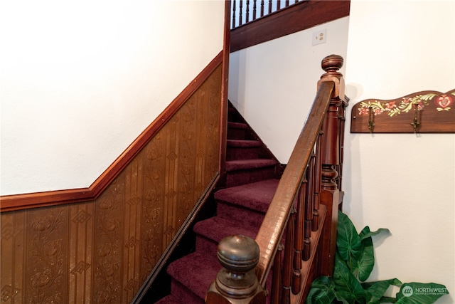 stairway featuring wooden walls