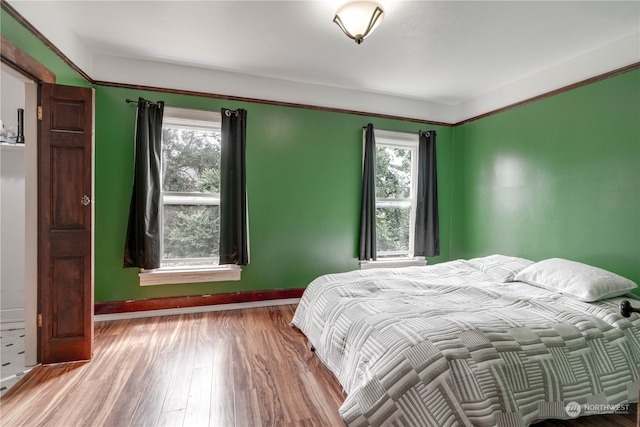 bedroom with multiple windows and hardwood / wood-style flooring