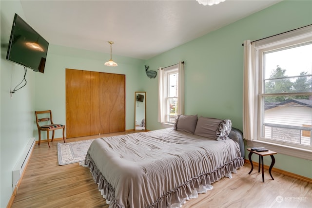 bedroom with a baseboard radiator and light hardwood / wood-style flooring