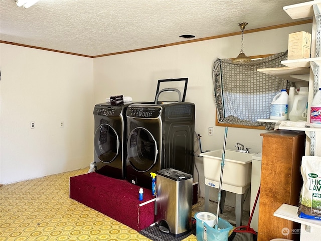 clothes washing area with sink, crown molding, a textured ceiling, and separate washer and dryer