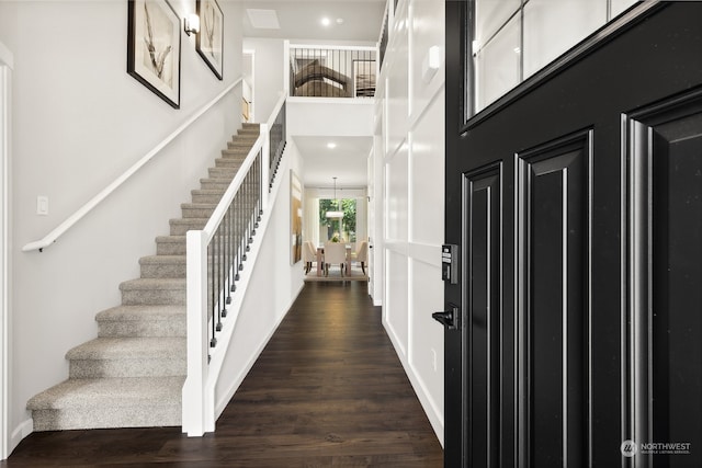 foyer entrance featuring dark wood-type flooring and a towering ceiling