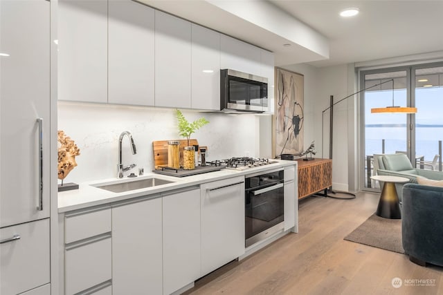 kitchen featuring white cabinets, light hardwood / wood-style flooring, appliances with stainless steel finishes, and sink