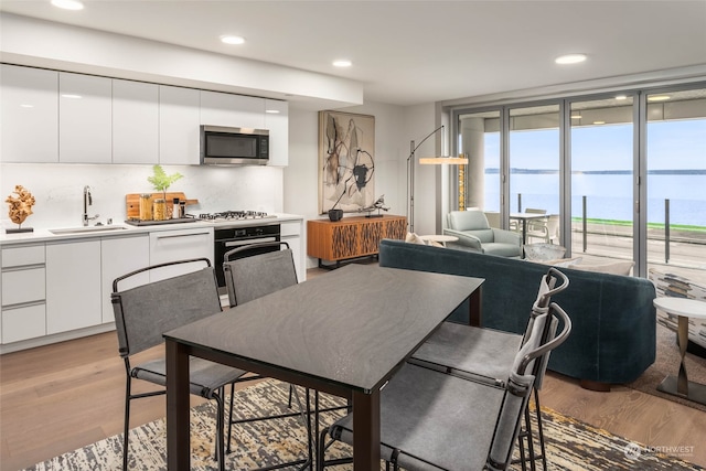 dining space featuring light hardwood / wood-style floors, sink, and a water view