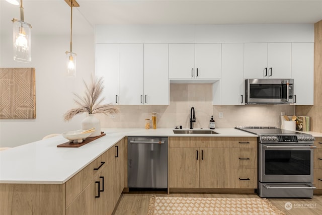 kitchen with white cabinetry, sink, pendant lighting, decorative backsplash, and appliances with stainless steel finishes