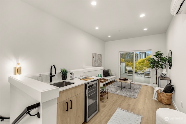 kitchen with a wall unit AC, beverage cooler, sink, light brown cabinets, and light hardwood / wood-style flooring