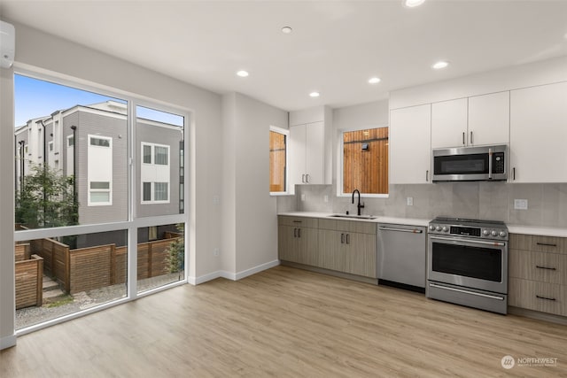 kitchen with white cabinets, light hardwood / wood-style floors, appliances with stainless steel finishes, and sink