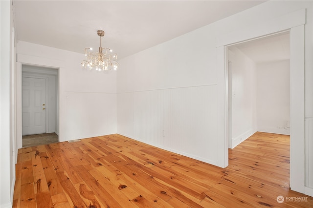 unfurnished room with a chandelier and light hardwood / wood-style floors