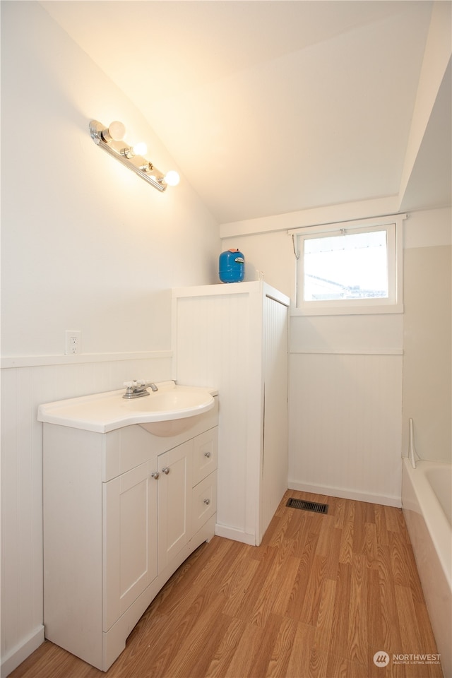 bathroom with hardwood / wood-style floors, lofted ceiling, shower / washtub combination, and vanity