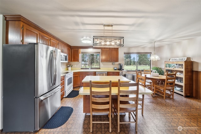 kitchen featuring stainless steel appliances, a notable chandelier, dark tile floors, and pendant lighting