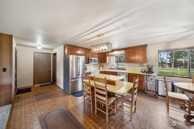 kitchen with hanging light fixtures, dark tile flooring, stainless steel appliances, and sink