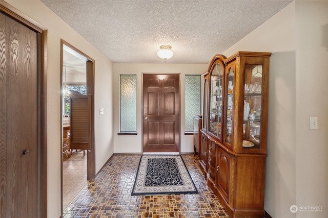 entrance foyer with dark tile floors and a textured ceiling