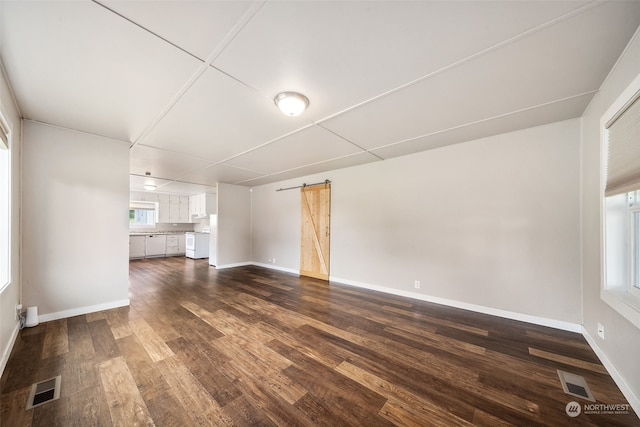 unfurnished living room featuring a barn door and dark hardwood / wood-style flooring