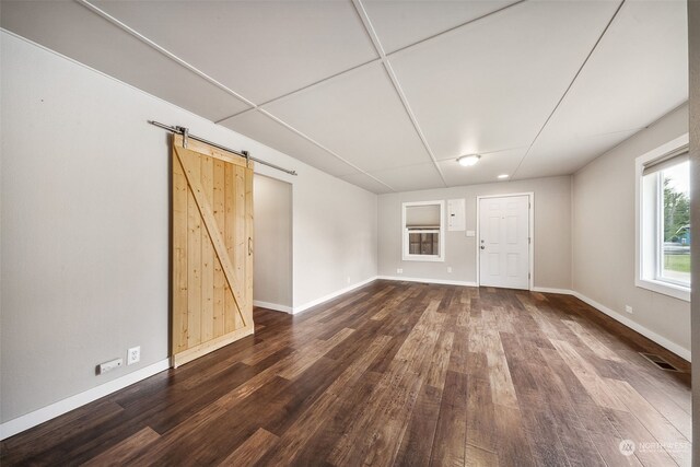 unfurnished living room with a barn door and dark wood-type flooring