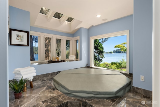 interior space with a water view, a skylight, and dark tile floors