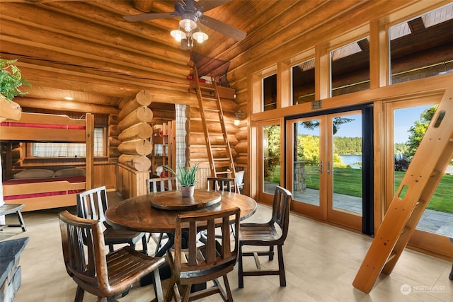 tiled dining room featuring french doors, rustic walls, ceiling fan, and a high ceiling