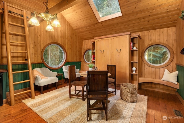 sitting room with wooden ceiling, hardwood / wood-style flooring, vaulted ceiling with skylight, and wooden walls