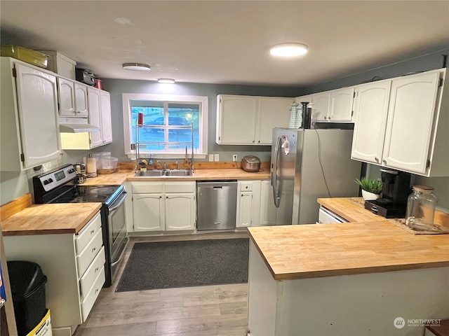 kitchen featuring light hardwood / wood-style flooring, appliances with stainless steel finishes, white cabinetry, butcher block counters, and sink