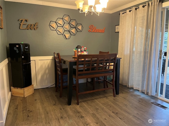 dining room with a notable chandelier, crown molding, and hardwood / wood-style flooring