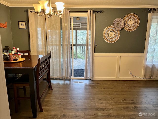 dining space with dark hardwood / wood-style floors, ornamental molding, and a chandelier