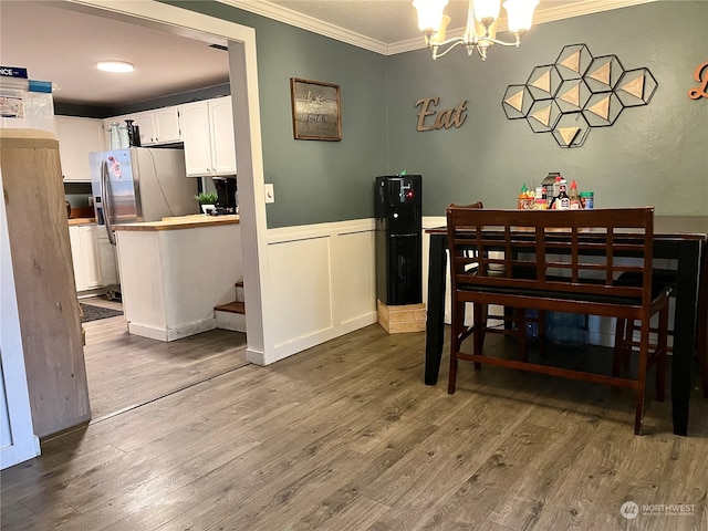 dining area with a chandelier, hardwood / wood-style flooring, and ornamental molding