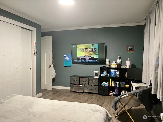 bedroom with dark hardwood / wood-style floors, ornamental molding, and a closet