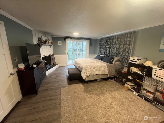 bedroom with a tiled fireplace, crown molding, dark hardwood / wood-style floors, access to exterior, and a textured ceiling