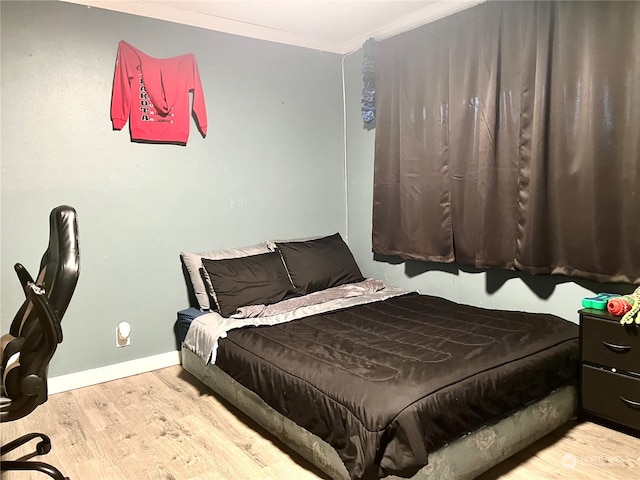 bedroom with light wood-type flooring and ornamental molding