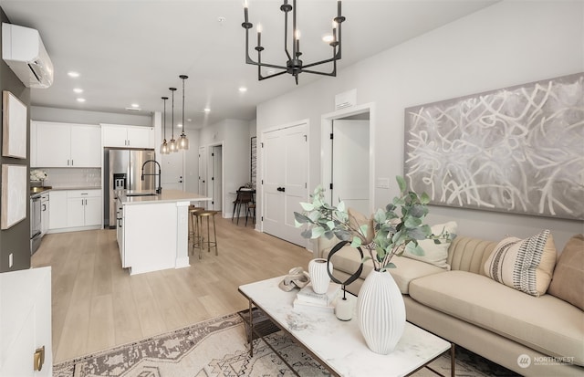 living room featuring an inviting chandelier, sink, light hardwood / wood-style floors, and a wall unit AC