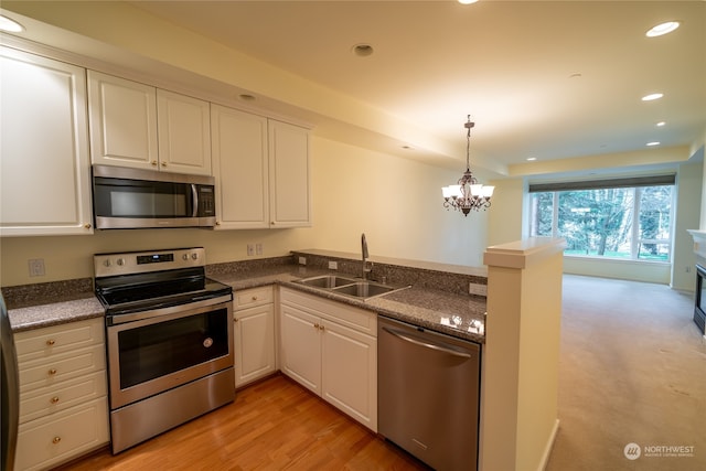 kitchen with stainless steel appliances, a notable chandelier, light hardwood / wood-style flooring, white cabinetry, and sink