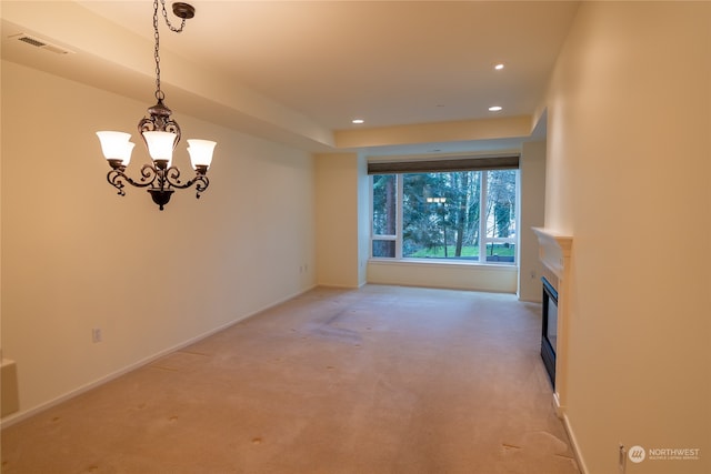 carpeted empty room with a notable chandelier