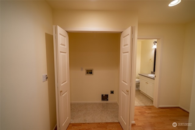 clothes washing area featuring hookup for an electric dryer, sink, light wood-type flooring, and hookup for a washing machine