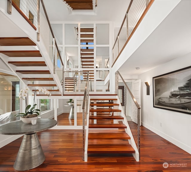 staircase with hardwood / wood-style floors and a high ceiling