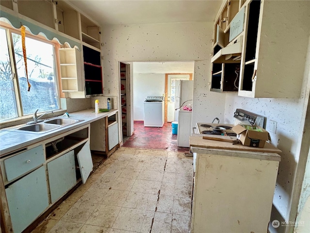 kitchen with washer / dryer, stove, sink, white refrigerator, and light tile floors