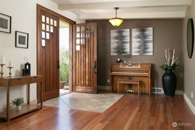 foyer featuring wood-type flooring, a wealth of natural light, and beam ceiling