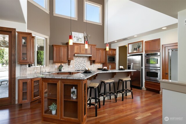 kitchen with a kitchen bar, appliances with stainless steel finishes, tasteful backsplash, a center island, and dark hardwood / wood-style flooring