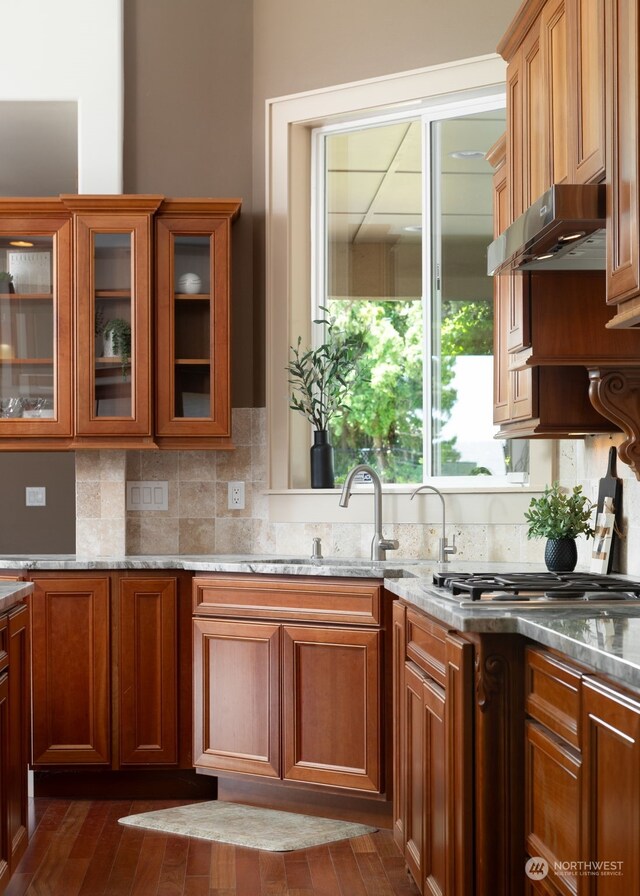 kitchen featuring stainless steel gas cooktop, dark hardwood / wood-style floors, backsplash, and stone countertops