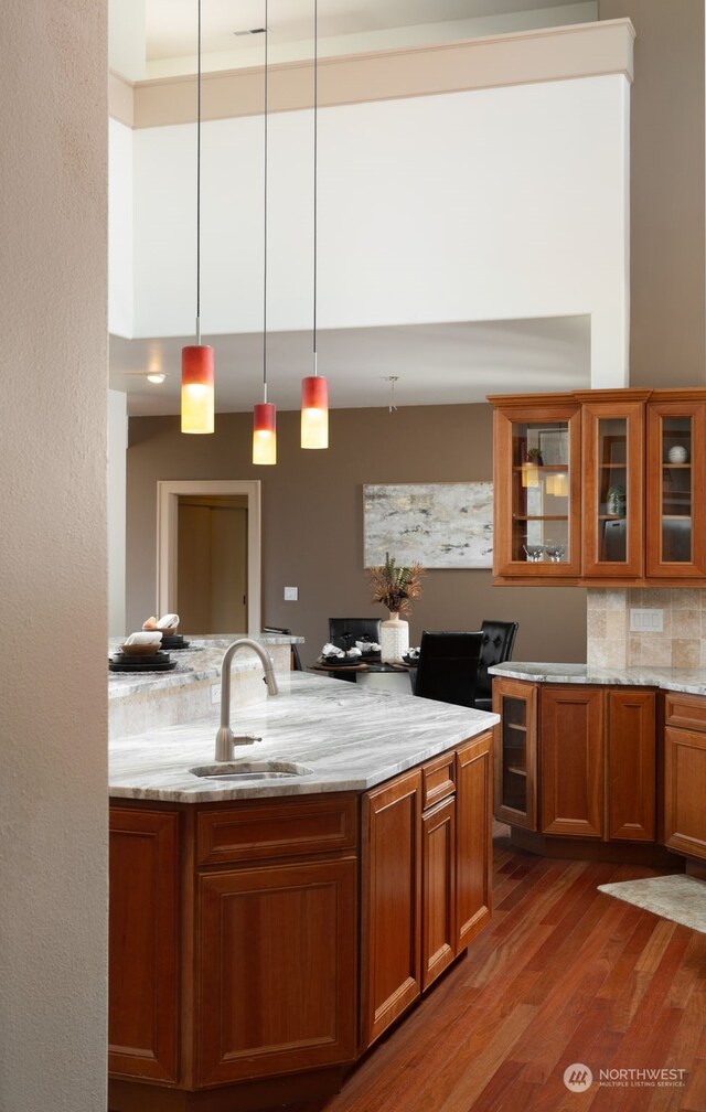 kitchen featuring sink, pendant lighting, wood-type flooring, and light stone counters