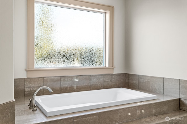 bathroom featuring tiled tub and a wealth of natural light