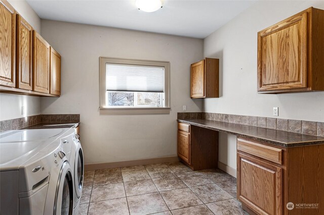 clothes washing area featuring light tile patterned flooring, cabinets, and washing machine and clothes dryer