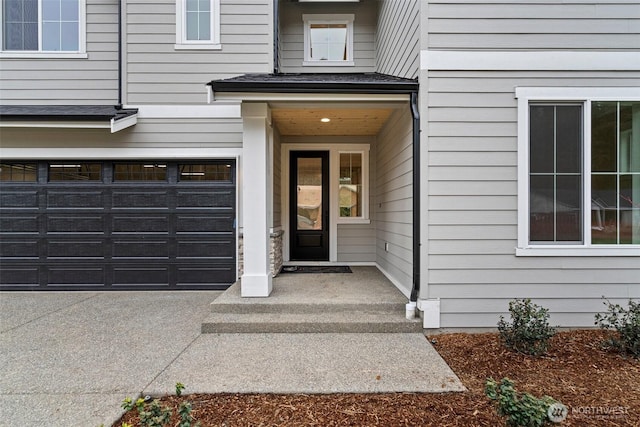 view of exterior entry with roof with shingles and an attached garage