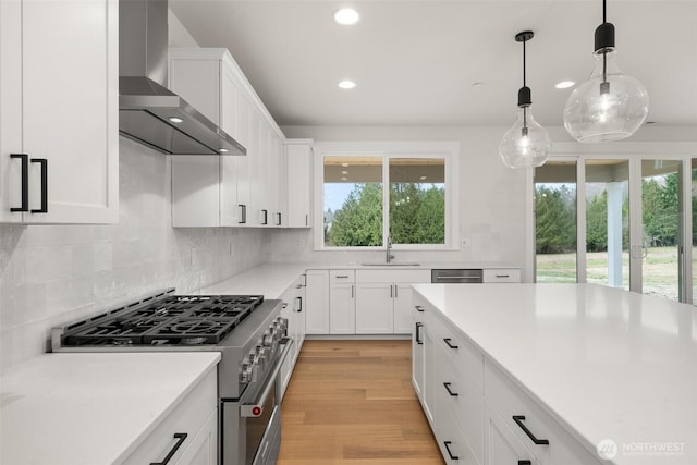 kitchen featuring white cabinetry, wall chimney exhaust hood, appliances with stainless steel finishes, and light countertops