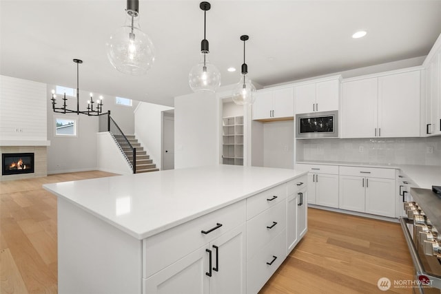 kitchen with stainless steel appliances, hanging light fixtures, light countertops, and a center island